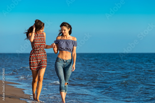Fotografie Pretty girl has a fun with her girlfriend on the beach