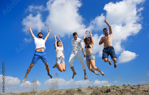 Obraz na plátně Image of five energetic people jumping at the beach
