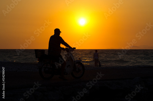 Fototapeta Naklejka Na Ścianę i Meble -  Motorcyclist on the beach during the sunset, Greece