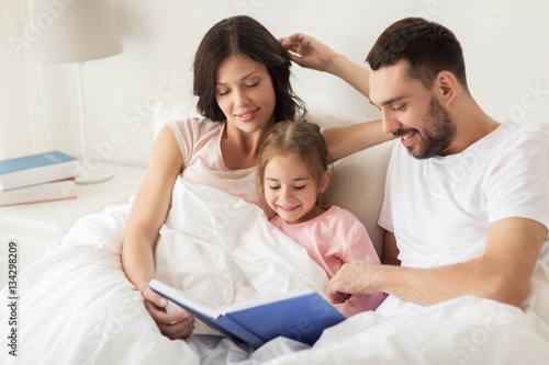 happy family reading book in bed at home
