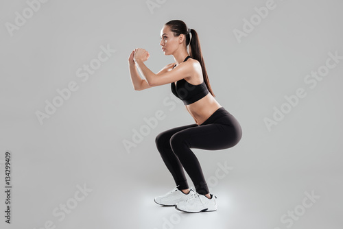 Full length of concentrated young woman athlete doing squats photo
