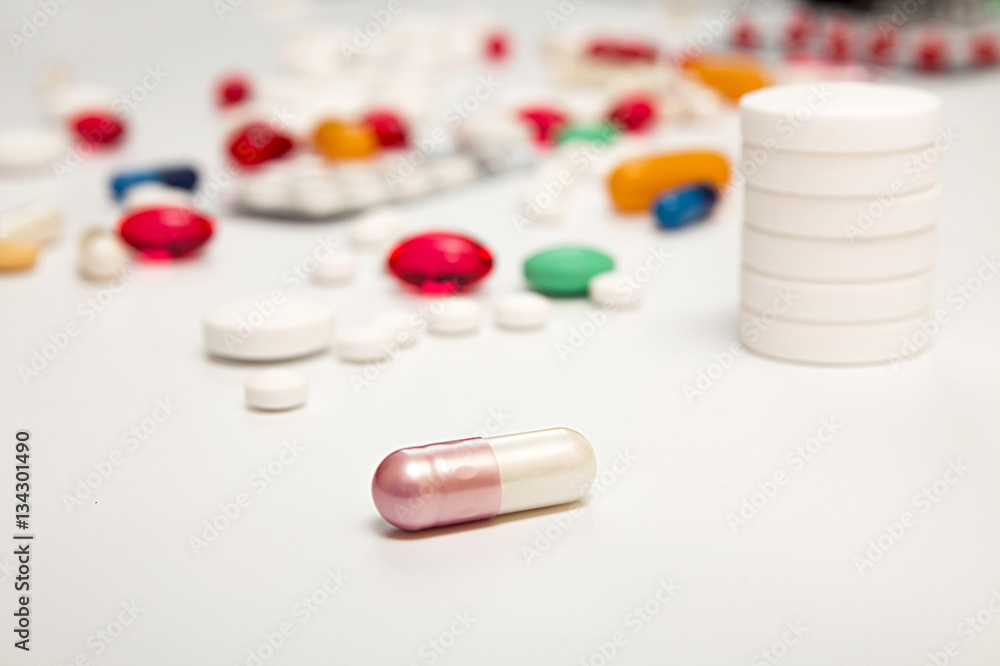 White pink medicine capsul on foreground. Heap of tablets backgr White pink medicine capsul on foreground. Heap of tablets backgr
