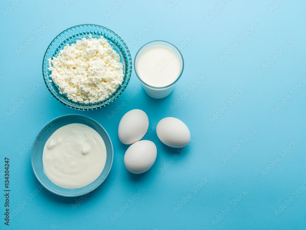 Protein products: cheese, cream, milk, eggs on the blue backgrou Protein products: cheese, cream, milk, eggs on the blue backgrou