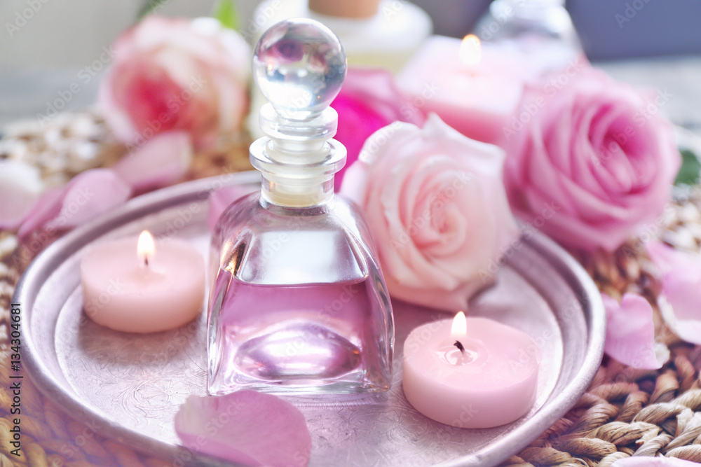 Essential oil with rose petals on silver plate Essential oil with rose petals on silver plate