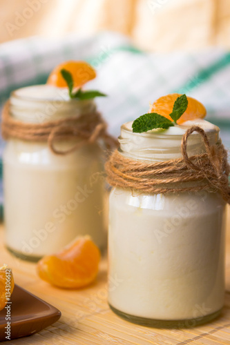 Fresh organig natural white yogurt in glass jars with tangerine photo