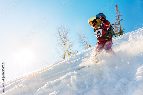 Freerider girl snowboarder slides from the mountain in the light