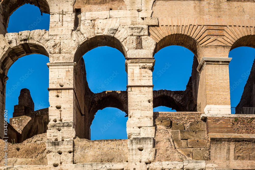 Detail of exterior arched openings / windows at the colosseum in Rome Italy, blue sky background.
