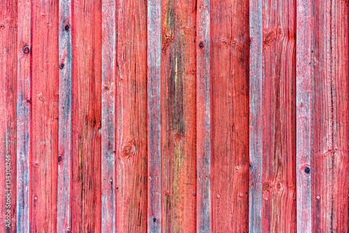 Wood barn wall with red peeling flaking color. Red wooden background texture.