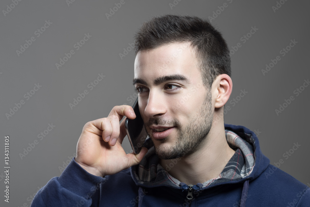 Happy relaxed young man talking on the mobile phone smiling and looking away Happy relaxed young man talking on the mobile phone smiling and looking away