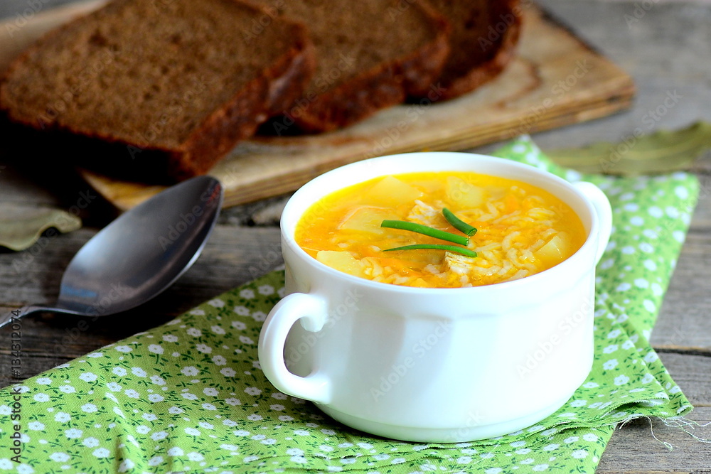 Easy rice soup. Home rice soup with meat, potatoes and carrots in a bowl. Bread pieces, spoon, green napkin on old wooden table. Dinner or lunch dish. Closeup Easy rice soup. Home rice soup with meat, potatoes and carrots in a bowl. Bread pieces, spoon, green napkin on old wooden table. Dinner or lunch dish. Closeup