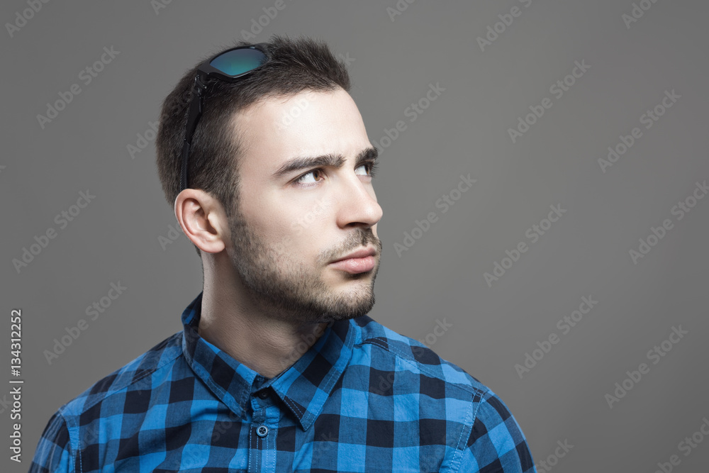 Annoyed young man with sunglasses in hair looking up at copyspace Annoyed young man with sunglasses in hair looking up at copyspace