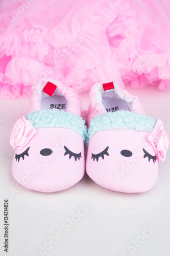 Pink little girlie baby shoes on a wooden floor