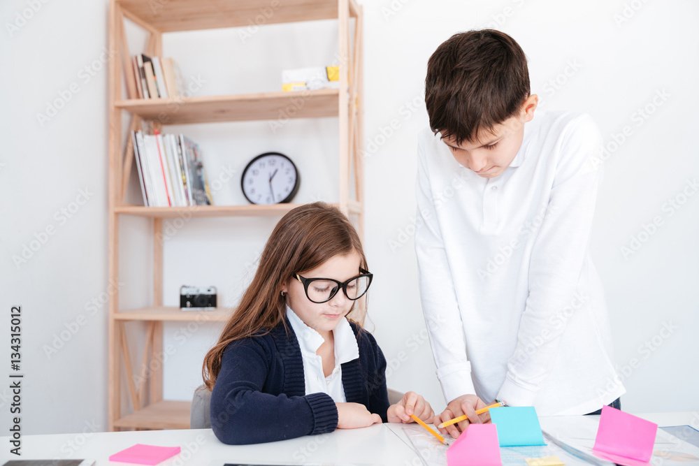 Boy standing and teaching little girl in glasses Boy standing and teaching little girl in glasses