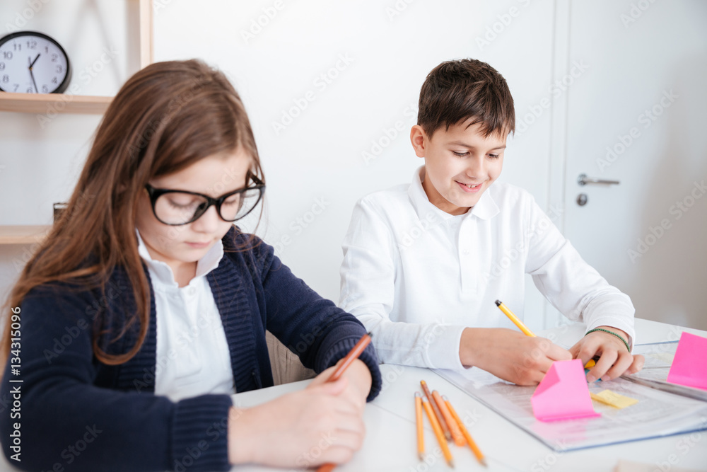 Two happy little chinldren writing at the table Two happy little chinldren writing at the table