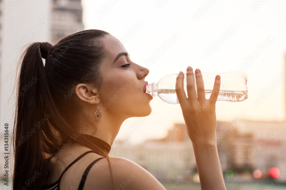 Woman drinking water from bottle. Side view of female face. Little sip of energy. Woman drinking water from bottle. Side view of female face. Little sip of energy.