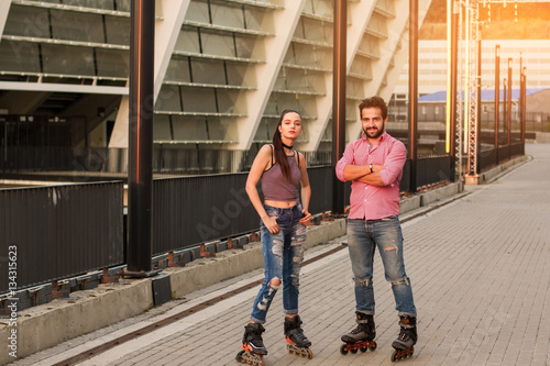 Young couple wearing inline skates. Man with crossed arms standing. We live by sport.
