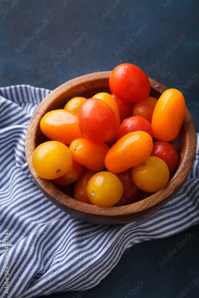 Cherry tomatoes with striped towel on blue background Cherry tomatoes with striped towel on blue background