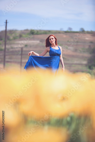 Woman in blue dress in yellow flower field