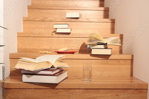 Bücher auf Holztreppe mit Imbiss und Wasserglas