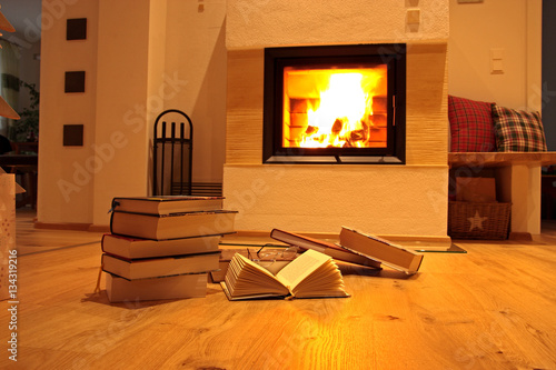 Bücherstapel auf Holzfußboden vor Kamin