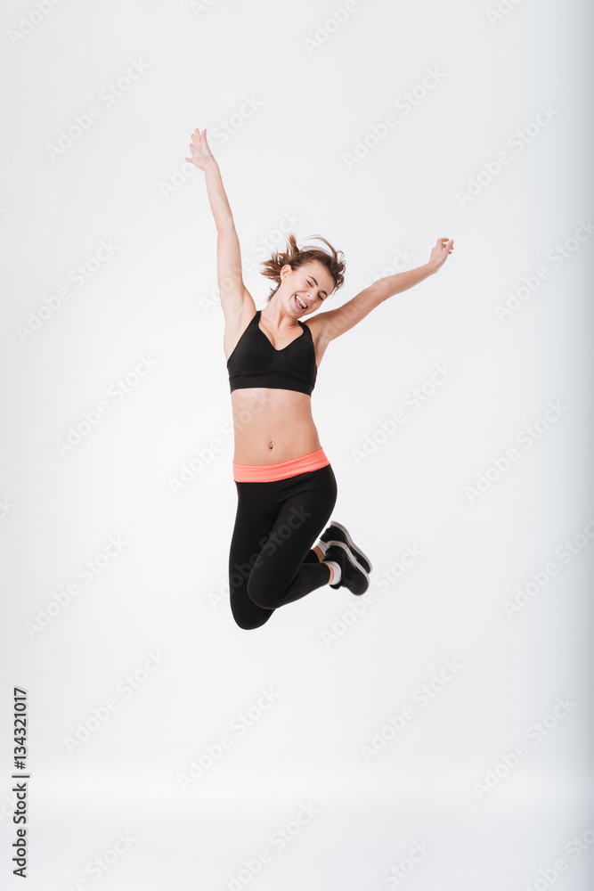 Happy young fitness woman jumping