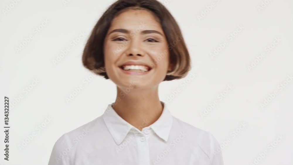 Young beautiful brunette east asian female in shirt touching and checking teeth with tongue smiling on white background Young beautiful brunette east asian female in shirt touching and checking teeth with tongue smiling on white background