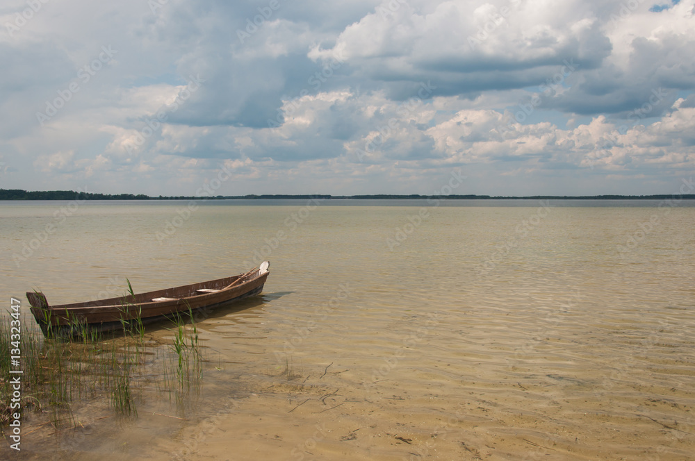 A lonely boat at the lovely Svityaz Lake, the deepest lake of Ukraine. Deep part is darker than coastal sand bottom.