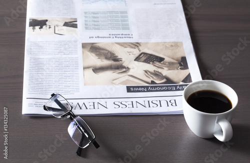 Newspaper with eyeglasses on wooden table photo