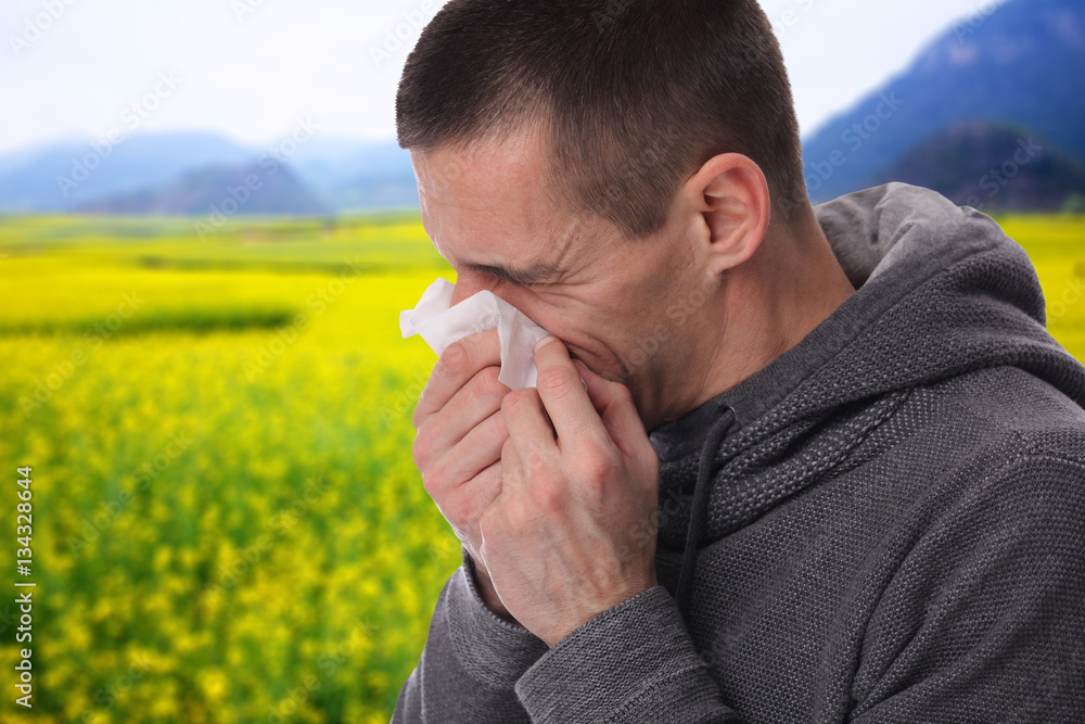 Pollen allergy, Springtime. Man sneezing in a tissue Pollen allergy, Springtime. Man sneezing in a tissue