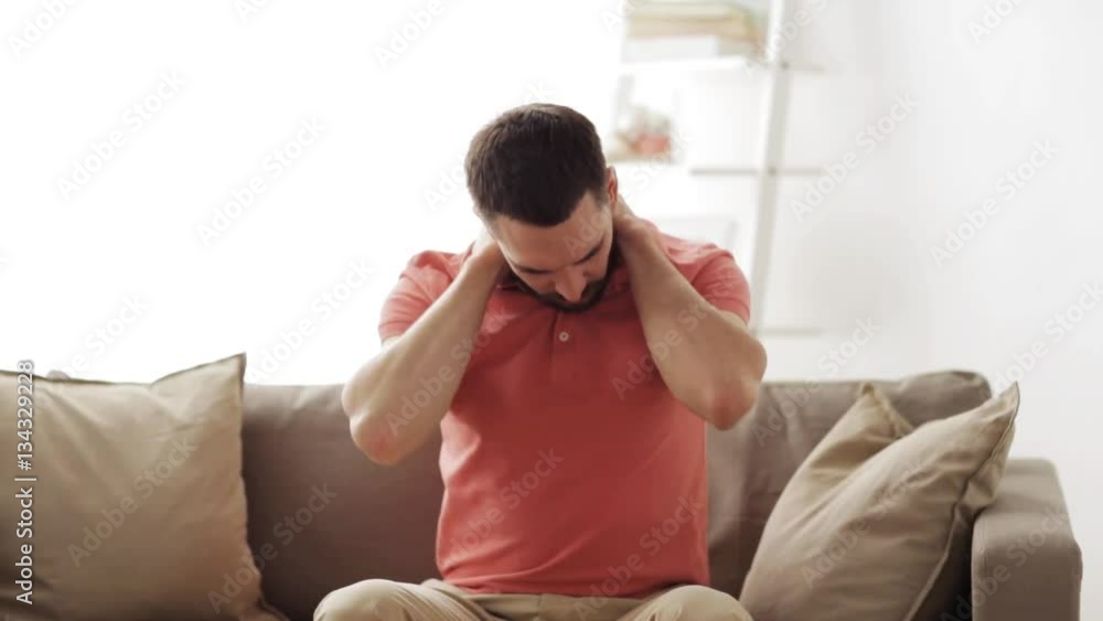 unhappy man suffering from neck pain at home unhappy man suffering from neck pain at home