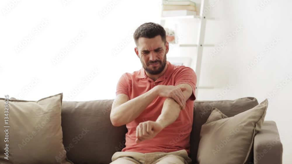 unhappy man suffering from pain in hand at home unhappy man suffering from pain in hand at home