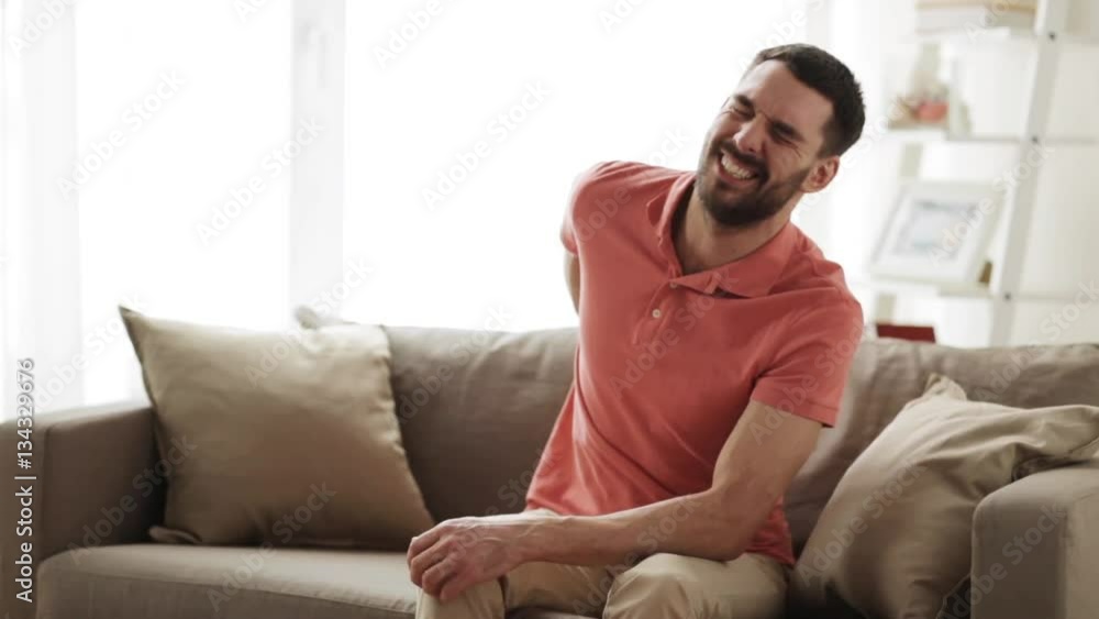 unhappy man suffering from backache at home