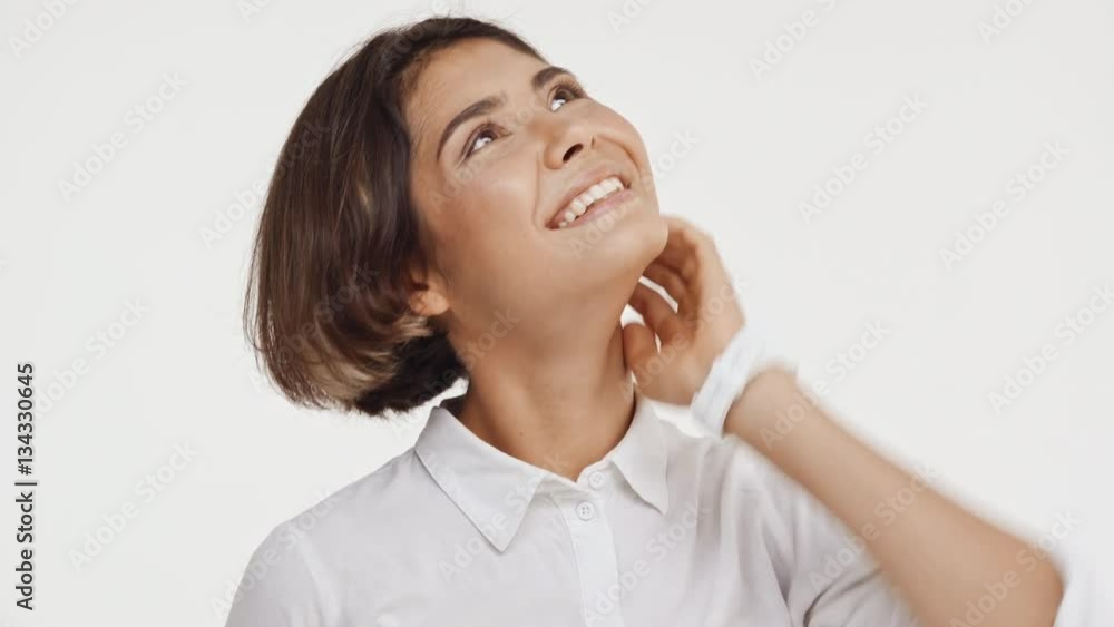 Young beautiful brunette east asian female in shirt looking up smiling in astonishment on white background Young beautiful brunette east asian female in shirt looking up smiling in astonishment on white background