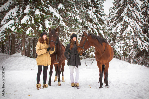 Twin sisters and horse in the winter forest