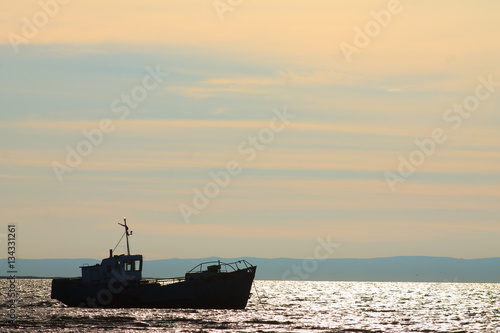 Beautiful view of the old fishing trawler at sunset © novolodskiy