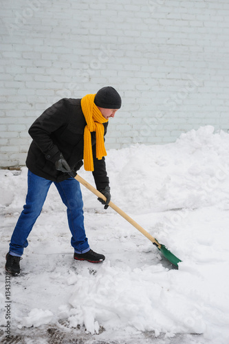 man in an orange scarf cleans snow