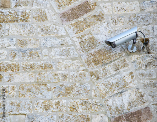 CCTV surveillance camera on stone background.