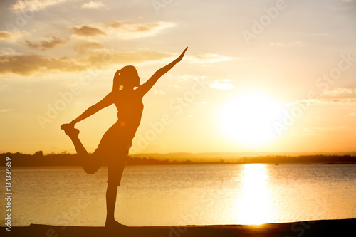 Silhouette woman with yoga posture at sunset.