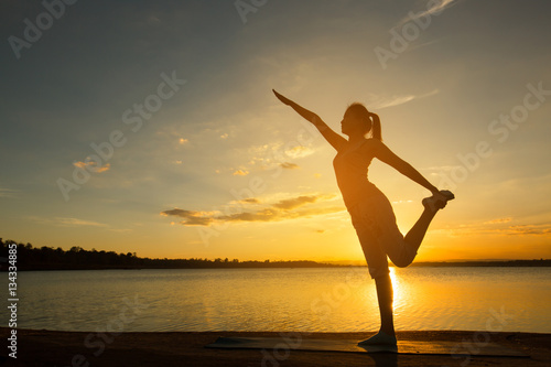 Silhouette woman with yoga posture  at sunset. © ittipol