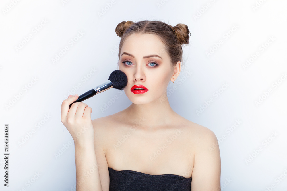 Young pretty woman trendy makeup bright red lips bun hairstyle bare shoulders act the ape with brush white studio background Young pretty woman trendy makeup bright red lips bun hairstyle bare shoulders act the ape with brush white studio background
