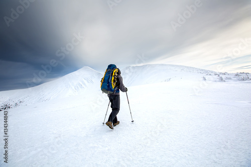 Man hiking in winter mountains before thunderstorm