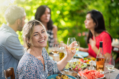 middle aged woman sitting on a terrace sharing meal with friends