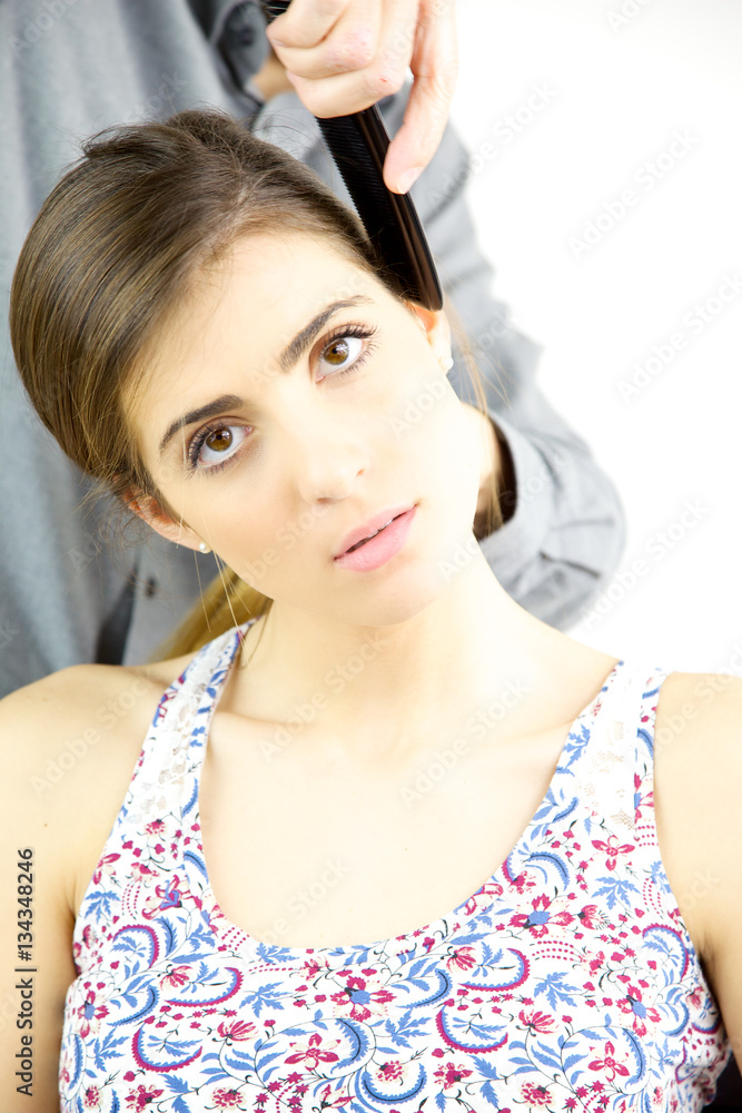 Woman getting hair brushed with comb by professional hair stylist looking camera Woman getting hair brushed with comb by professional hair stylist looking camera