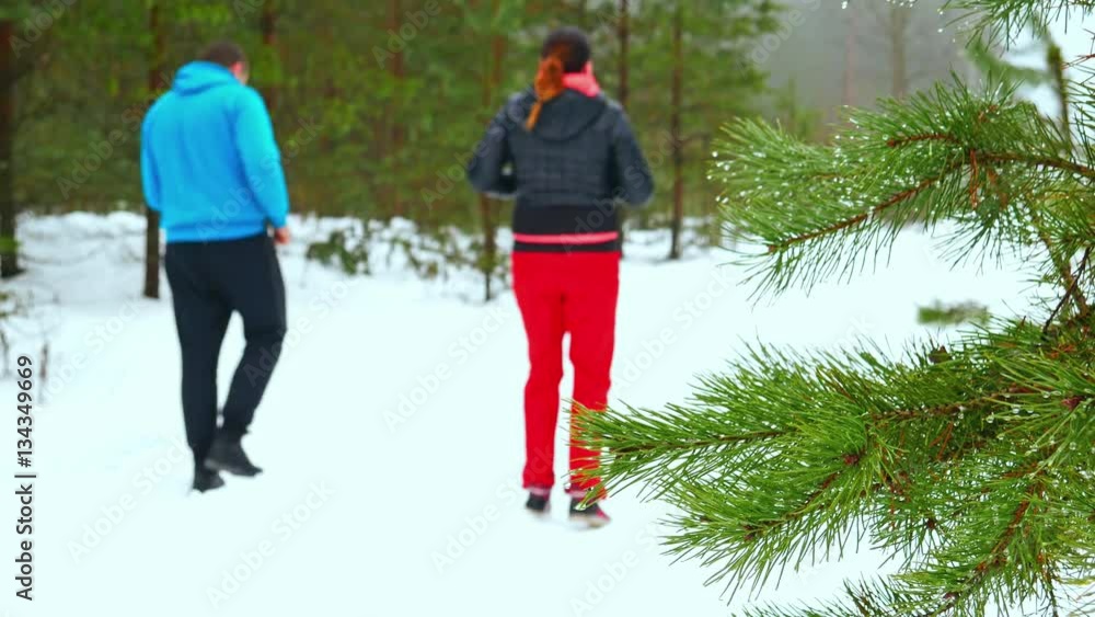 Man and woman run through snow-covered woodland. Man and woman run through snow-covered woodland.