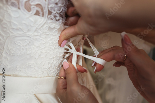 Close-up of woman s fingers lacing up bride s corset