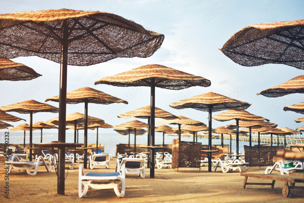 tinted image hotel beach area with umbrellas and sun loungers, h