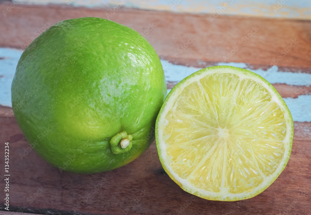 Fresh green lemon on wooden table background, Close up image Fresh green lemon on wooden table background, Close up image