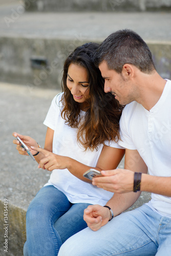 Young couple dating and using their smartphones. Man and woman using cellphones outside.  Modern relationship and technology use concept.