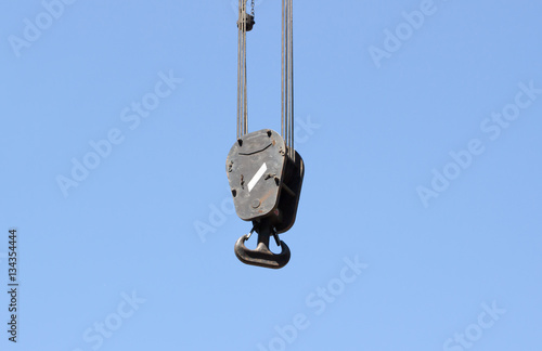 Cranes hooks hanging on steel ropes isolated on blue sky background.