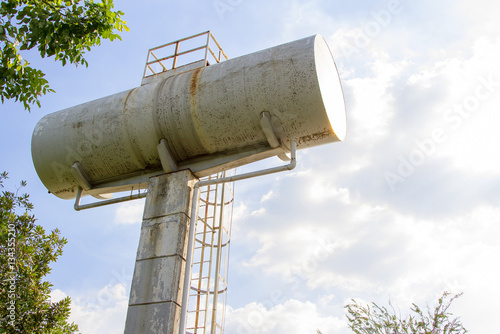 Water tower against the blue sky and old white tank